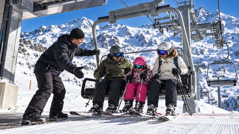 Trabajador de remontes de Candanchú ayudando a una familia a subir al telesilla en el Pirineo de Huesca